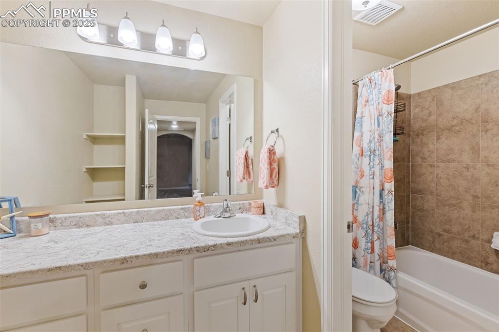 Image 18 of 33: Bathroom with shower / bath combo with shower curtain and vanity