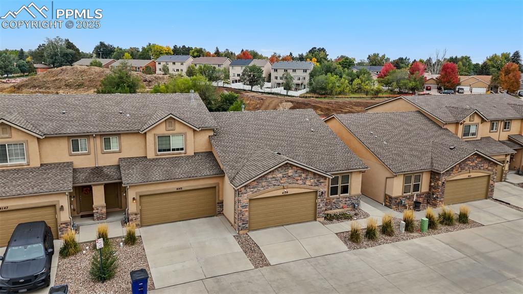 Image 23 of 33: View of front of home with stucco siding, stone siding, concrete driveway,
