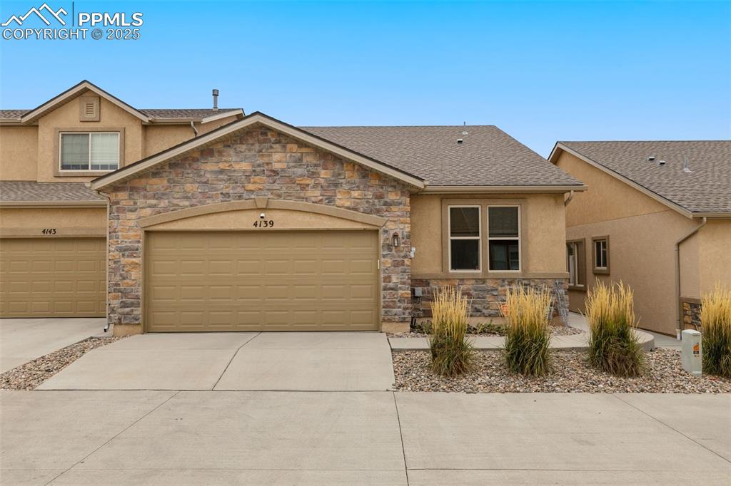 Image 29 of 33: View of front of property featuring stone siding, concrete driveway, stucco