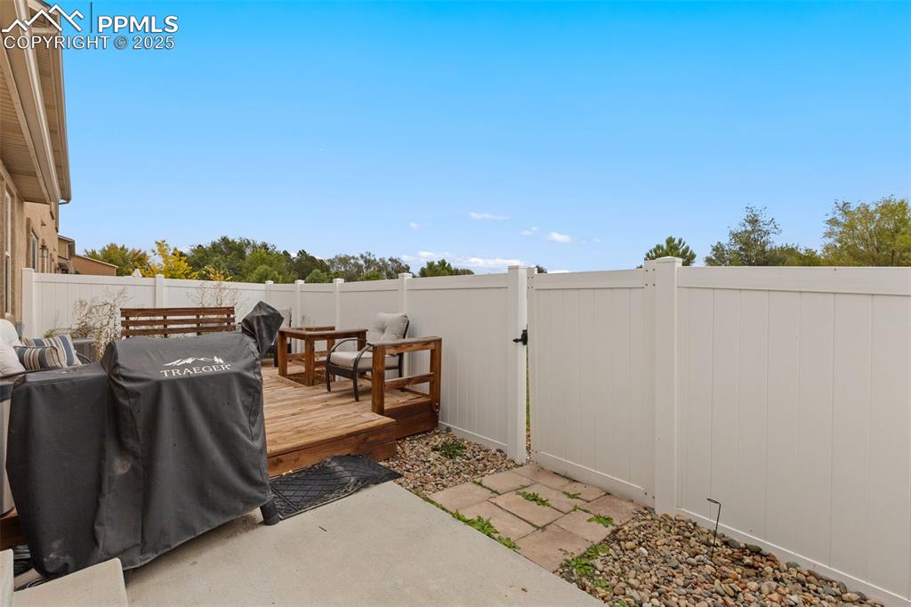 Image 30 of 33: Fenced backyard featuring a wooden deck and a grill