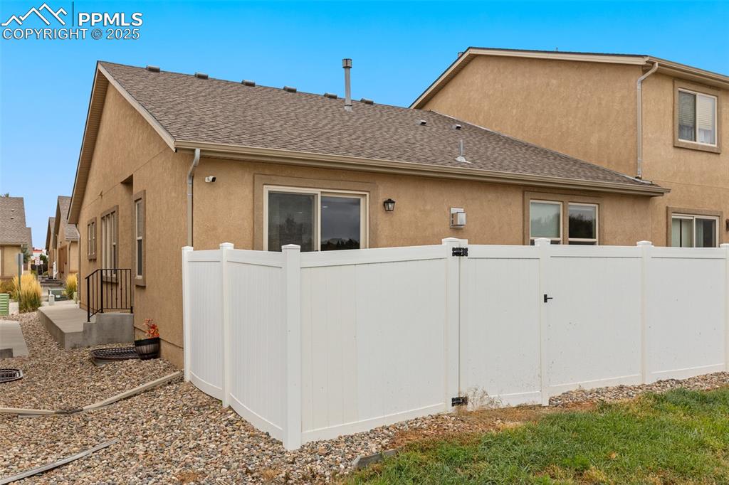 Image 32 of 33: View of side of property with stucco siding and roof with shingles