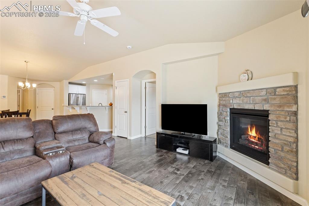 Image 4 of 33: Living area with lofted ceiling, wood finished floors, a stone fireplace, a