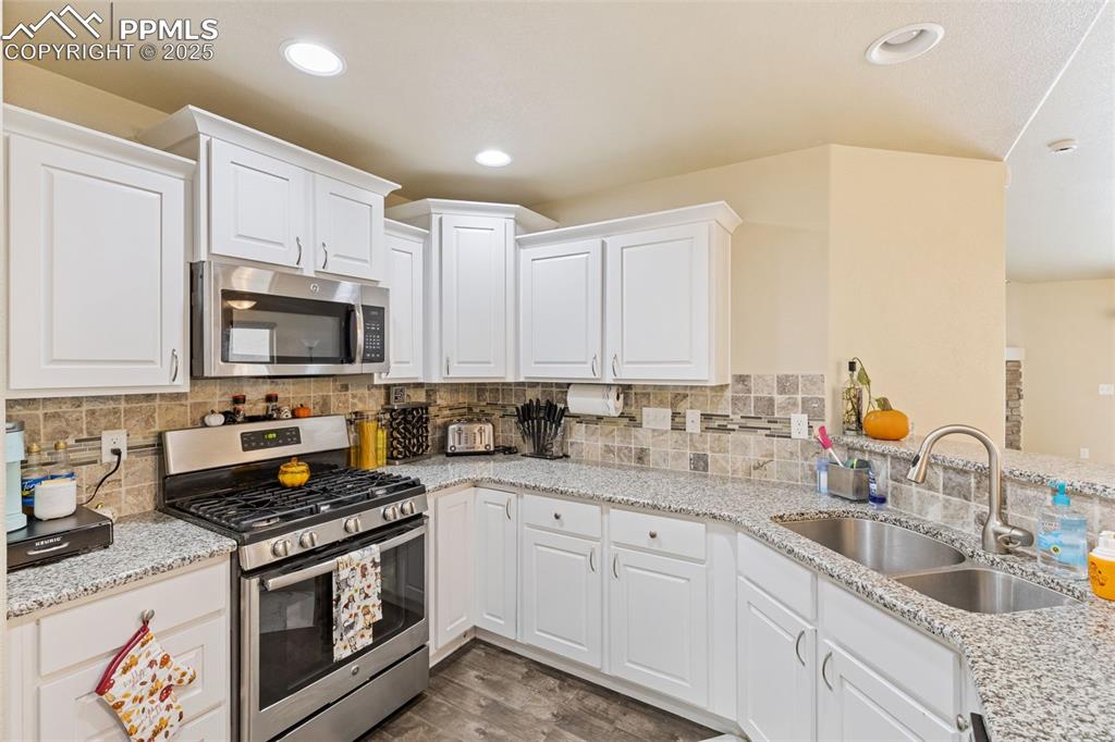 Image 5 of 33: Kitchen with appliances with stainless steel finishes, light stone counters