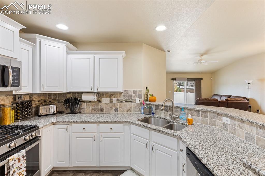 Image 6 of 33: Kitchen featuring white cabinets, light stone countertops, recessed lightin
