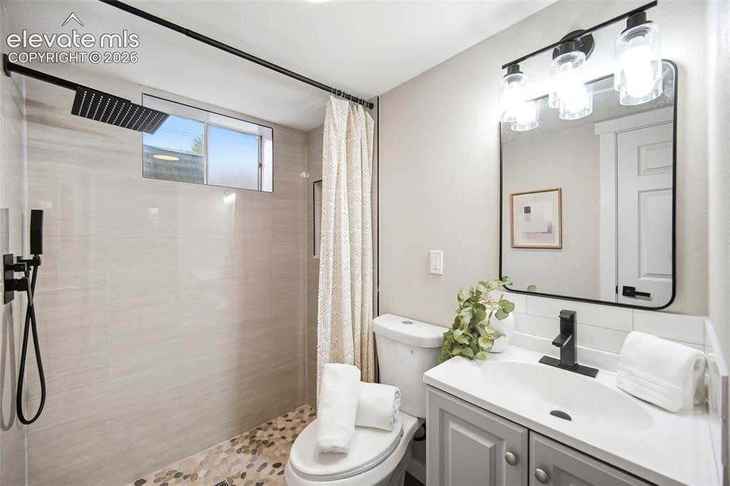 Image 18 of 26: Walk-in shower with pebble flooring and matte black fixtures