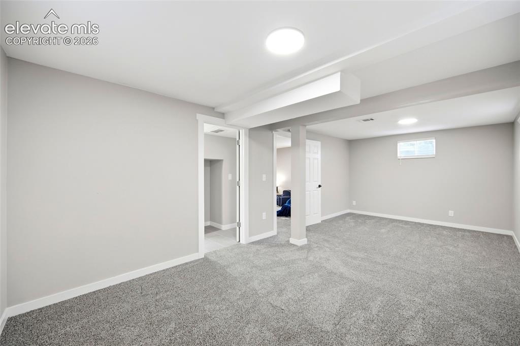 Image 21 of 26: Spacious room with plush gray carpeting, recessed ceiling lighting, and lig