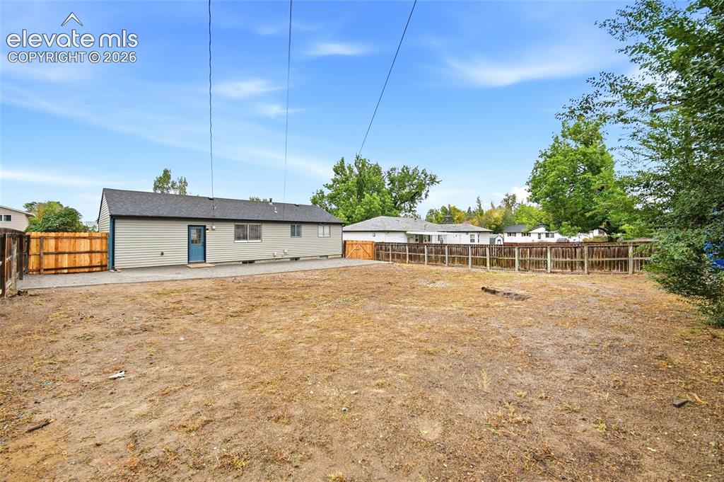 Image 23 of 26: Spacious yard with fencing, gravel patio area, and exterior siding