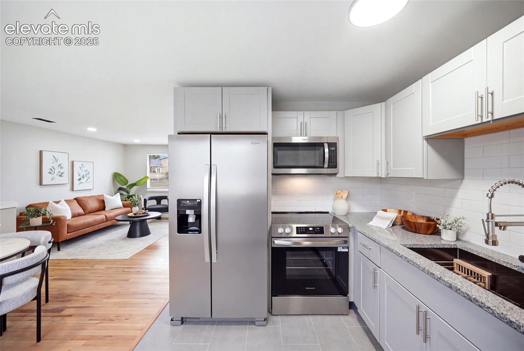 Image 7 of 26: Kitchen featuring stainless steel appliances, light gray cabinetry, and a s