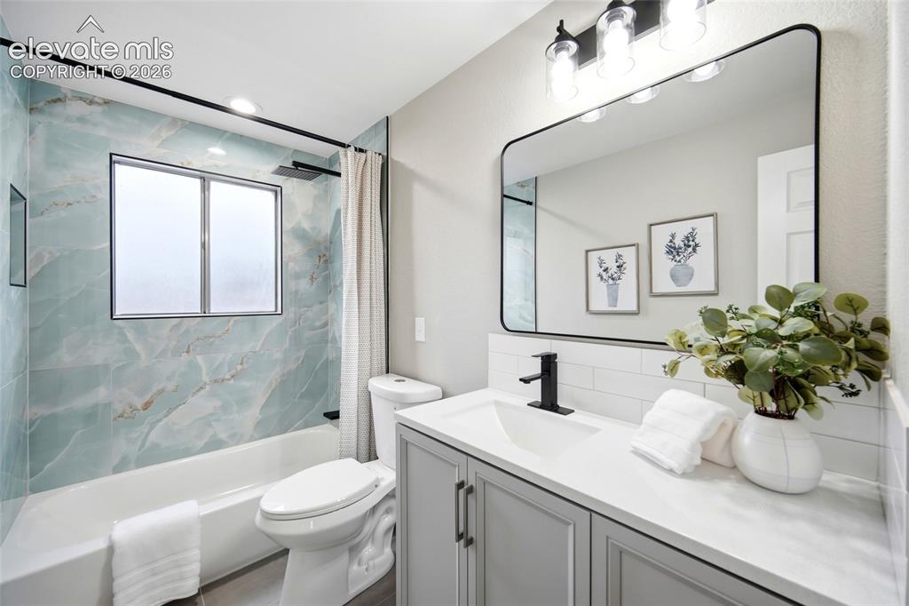 Image 8 of 26: Light gray vanity with dual cabinet doors and matte black hardware, white c