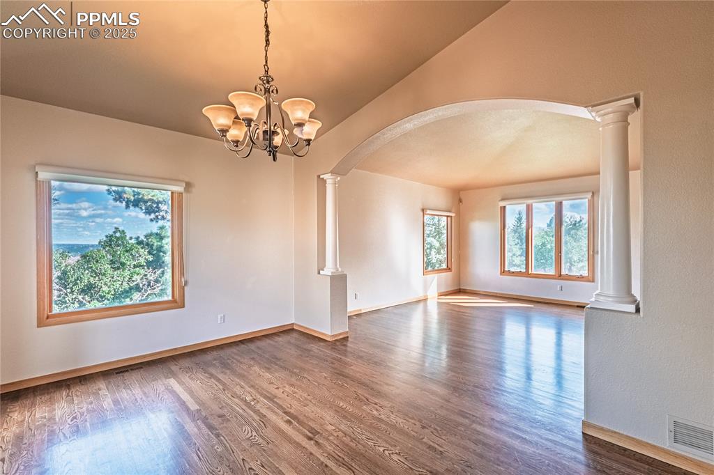 Image 13 of 45: Dining room with dark wood finished floors, vaulted ceilings.
