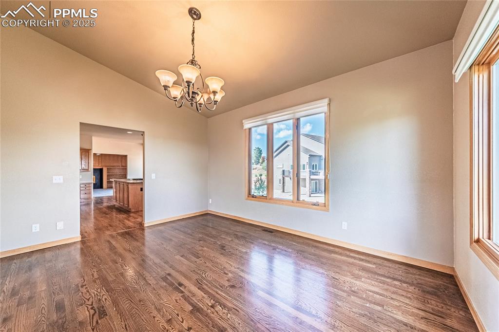 Image 15 of 45: Dining area with dark wood-style flooring, a chandelier, and lofted ceiling