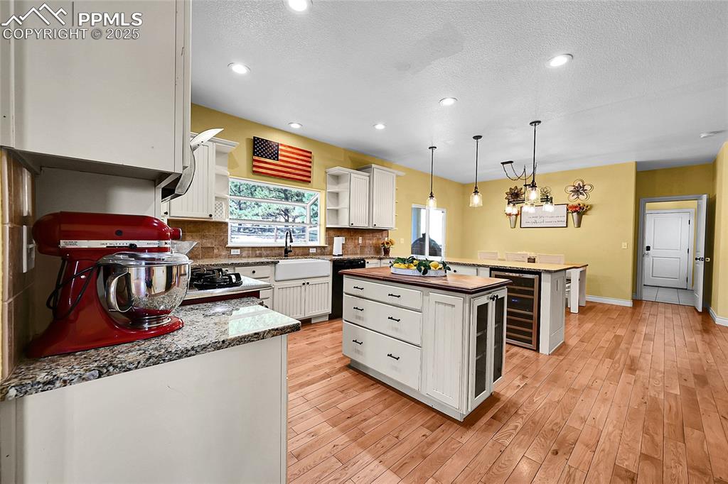 Image 16 of 50: kitchen island, farm style sink, wine fridge, breakfast bar, pantry