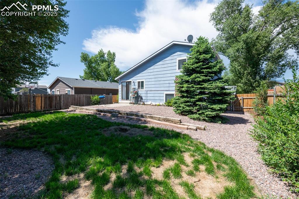 Image 21 of 25: Back of house featuring a fenced backyard