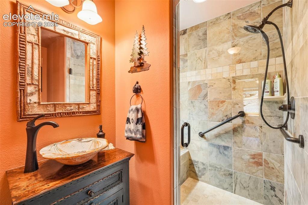 Image 8 of 50: 3/4 bathroom on main level with custom stand in shower and sink