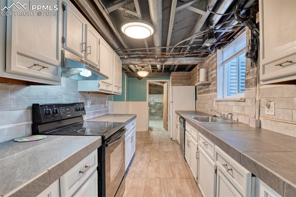 Image 21 of 47: Second Kitchen with under cabinet range hood, decorative backsplash, dishwa