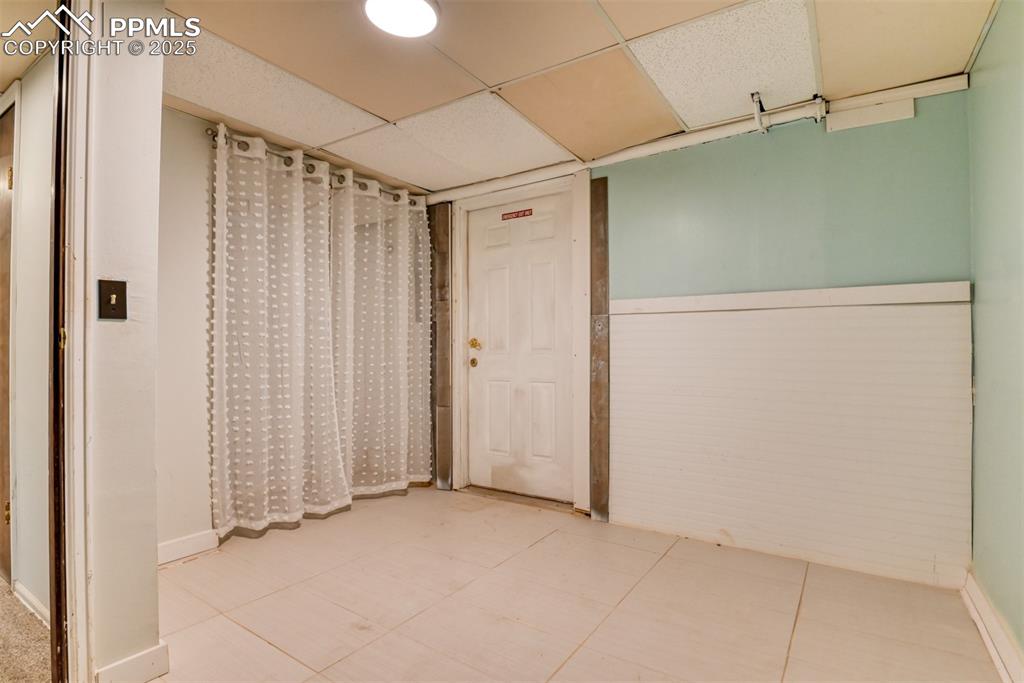 Image 28 of 47: Unfurnished room with a paneled ceiling and light tile patterned flooring