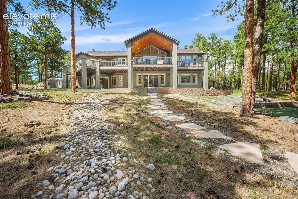 Image 21 of 42: Multi-level exterior with multiple balconies, a walk-out lower level, and a