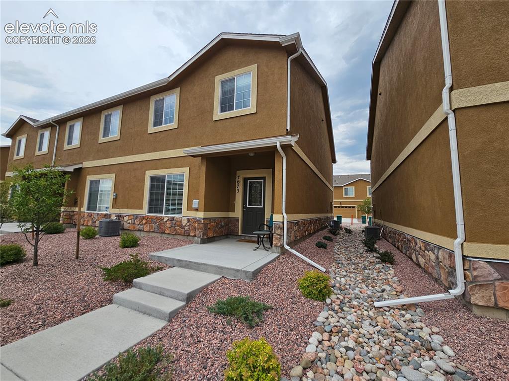 Caption: Brown stucco exterior featuring a stone facade accent, white trim, and a concrete walkway leading to