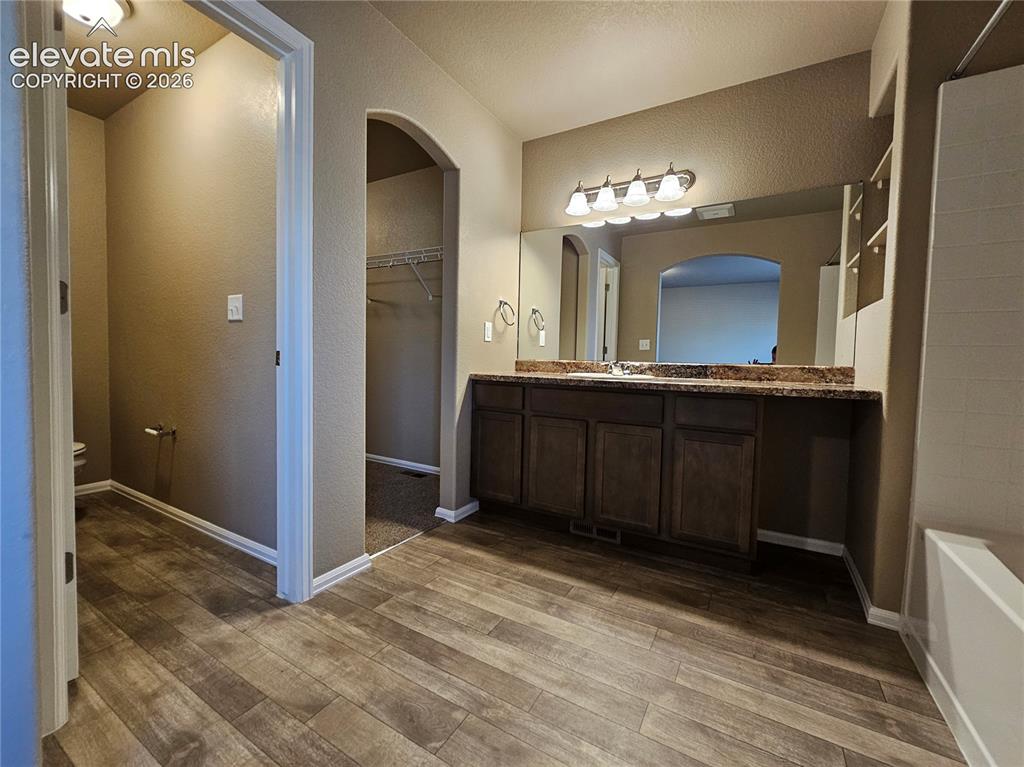 Image 10 of 20: Bathroom featuring wood-finish flooring, a vanity with dark wood cabinetry,