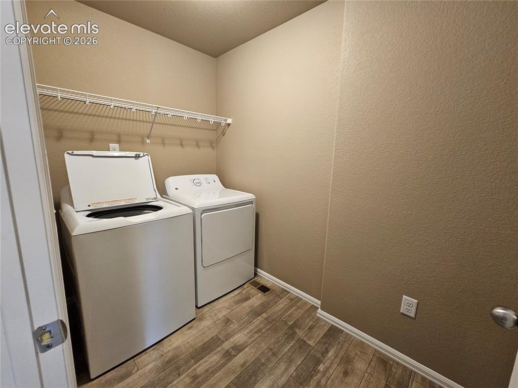 Image 13 of 20: Laundry area featuring wood-finish flooring, neutral wall tones, and a whit