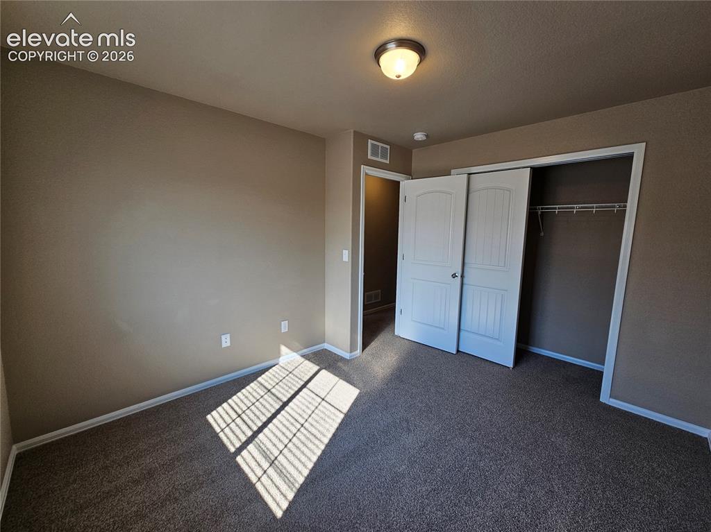 Image 15 of 20: Carpeted room featuring a built-in closet with bi-fold doors, neutral wall