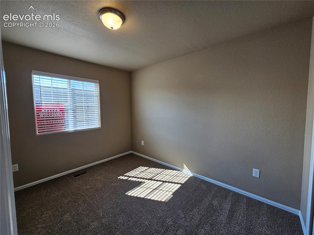 Image 17 of 20: Interior room featuring neutral-toned walls, textured ceiling, and dark pat