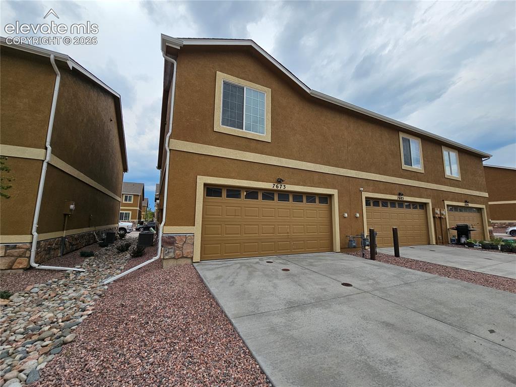 Image 19 of 20: Multi-story exterior with stucco siding and stone detailing