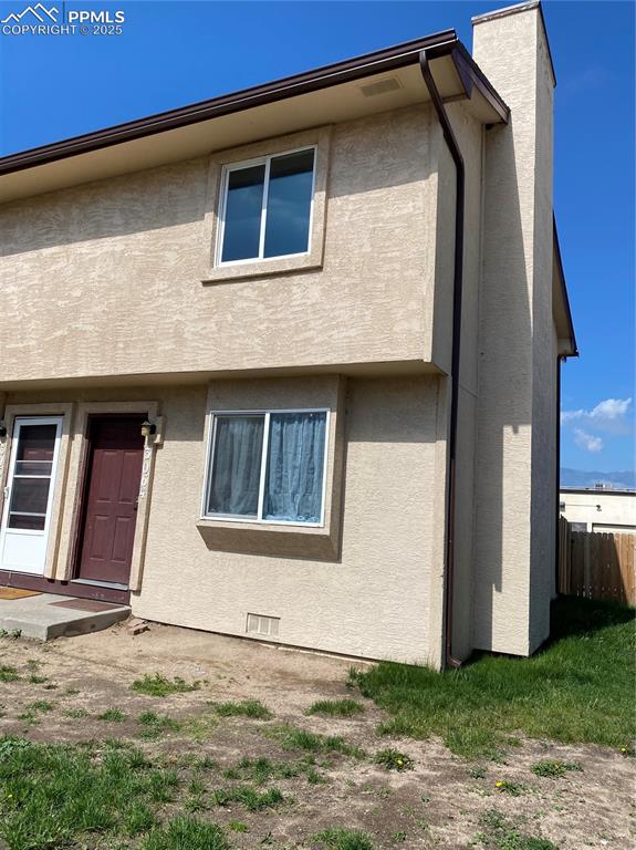Caption: Side view of home,featuring a chimney,stucco siding and convenient covered parking.