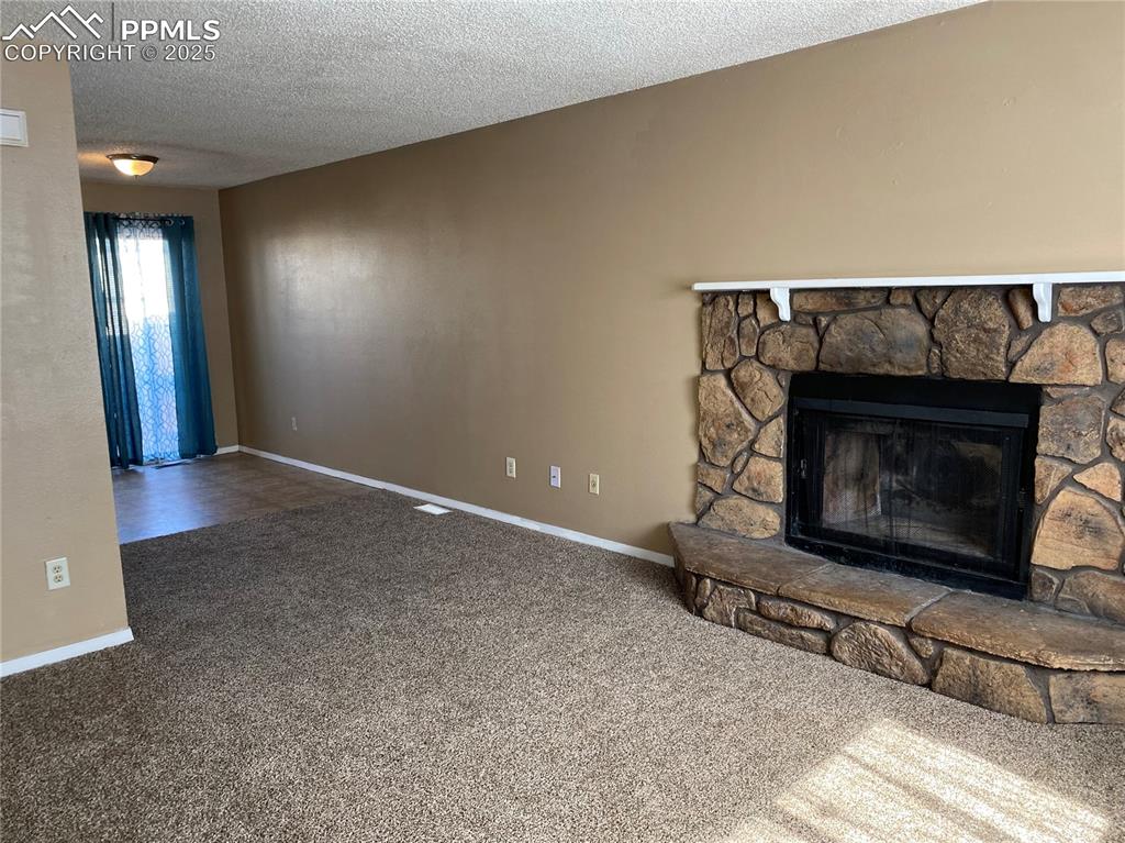 Image 2 of 15: living room with carpet floors, and a stone fireplace