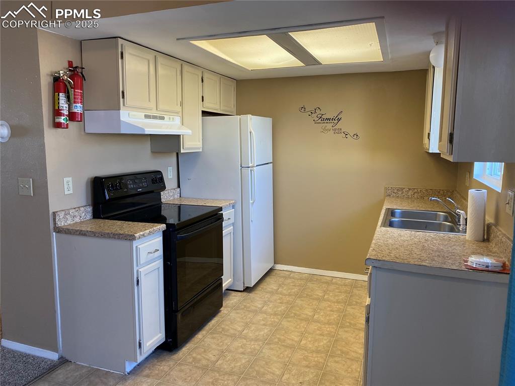 Image 4 of 15: Kitchen featuring black electric range oven, a sink, under cabinet range ho