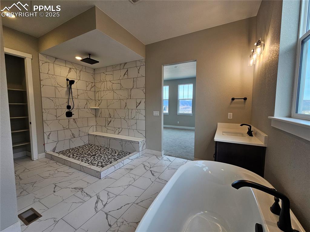 Image 11 of 20: Full bath with a freestanding tub, vanity, light marble finish flooring, ti