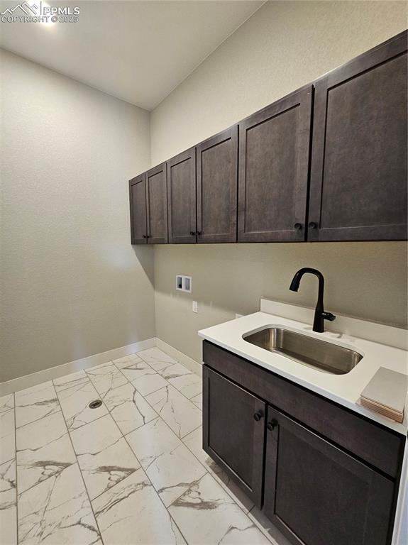 Image 19 of 20: Laundry room with light marble finish floors, washer hookup, and cabinet sp