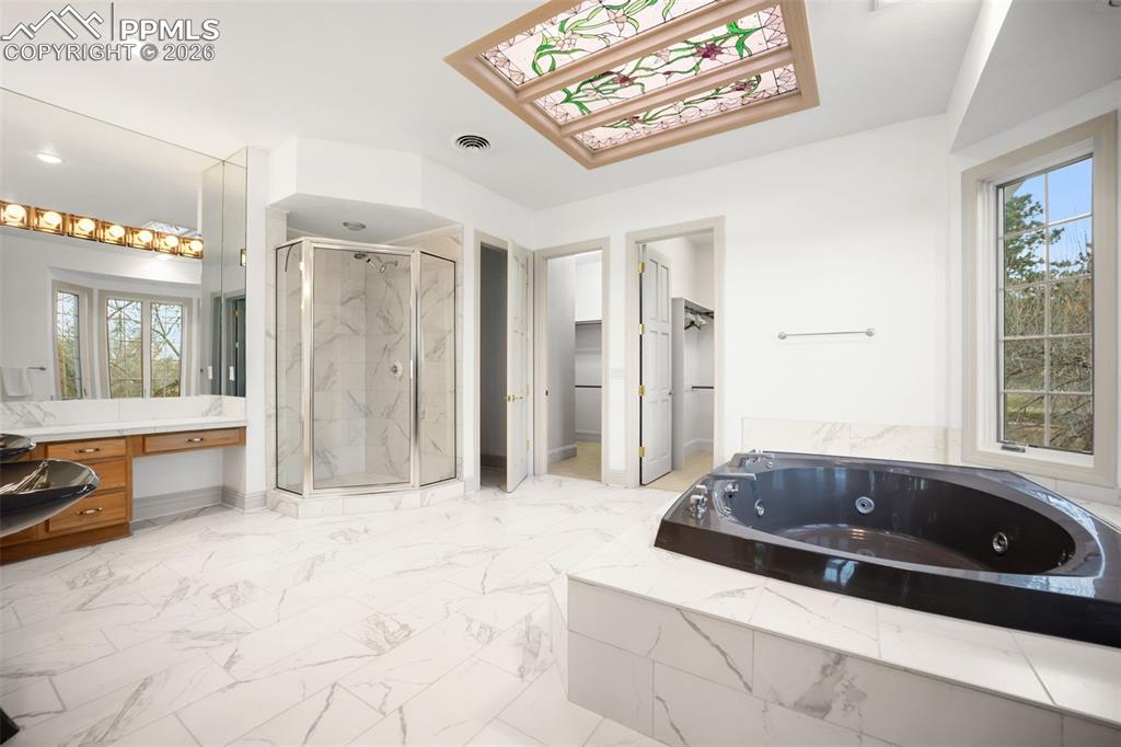 Image 27 of 50: Primary Bathroom with double sinks, vanity area and jetted tub with standin