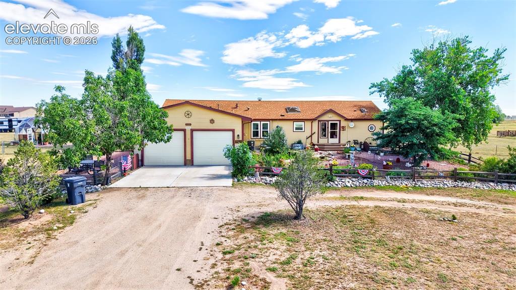 Image 1 of 38: Single-story residence featuring a two-car garage, expansive dirt driveway,