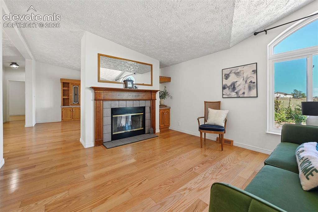 Image 12 of 38: Hardwood flooring throughout, a fireplace with a wood mantel and tile surro