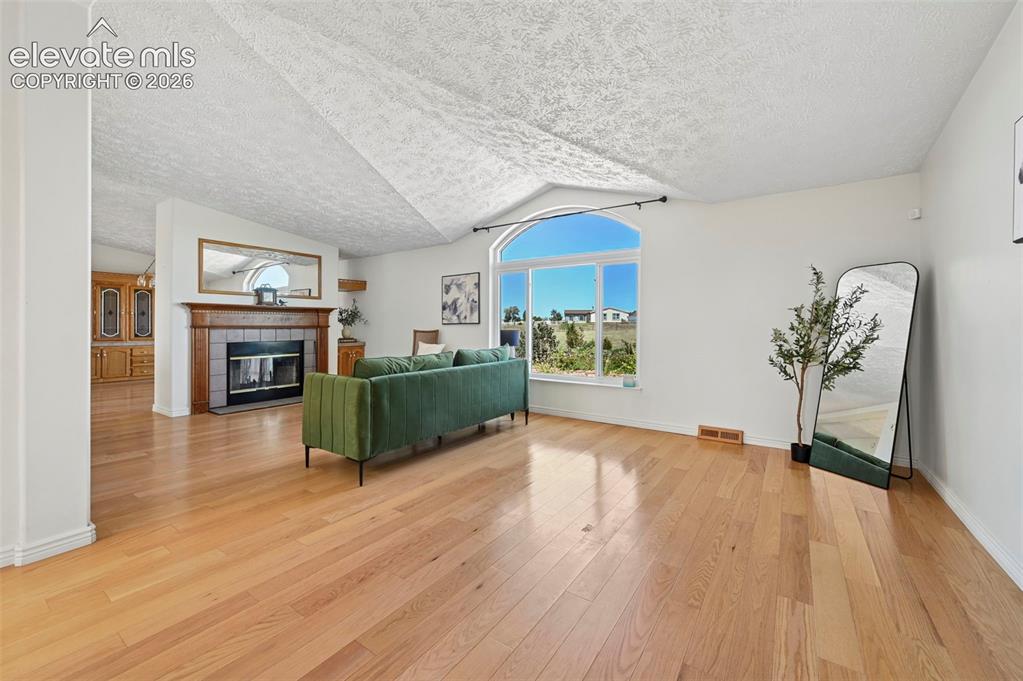 Image 13 of 38: Hardwood flooring throughout, vaulted ceiling, arched window, fireplace wit