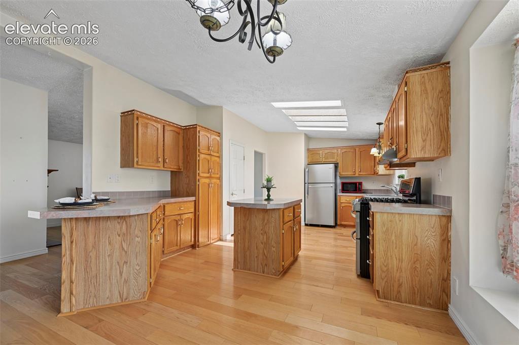 Image 15 of 38: Kitchen featuring wood-finish flooring, wood cabinetry, a center island, st