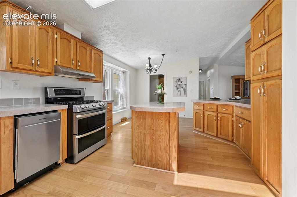 Image 18 of 38: Kitchen featuring wood-finish cabinetry, stainless steel appliances, a cent