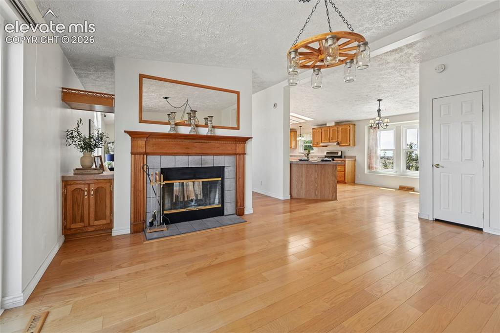 Image 19 of 38: Hardwood flooring throughout, a fireplace with a wood mantel and tile surro
