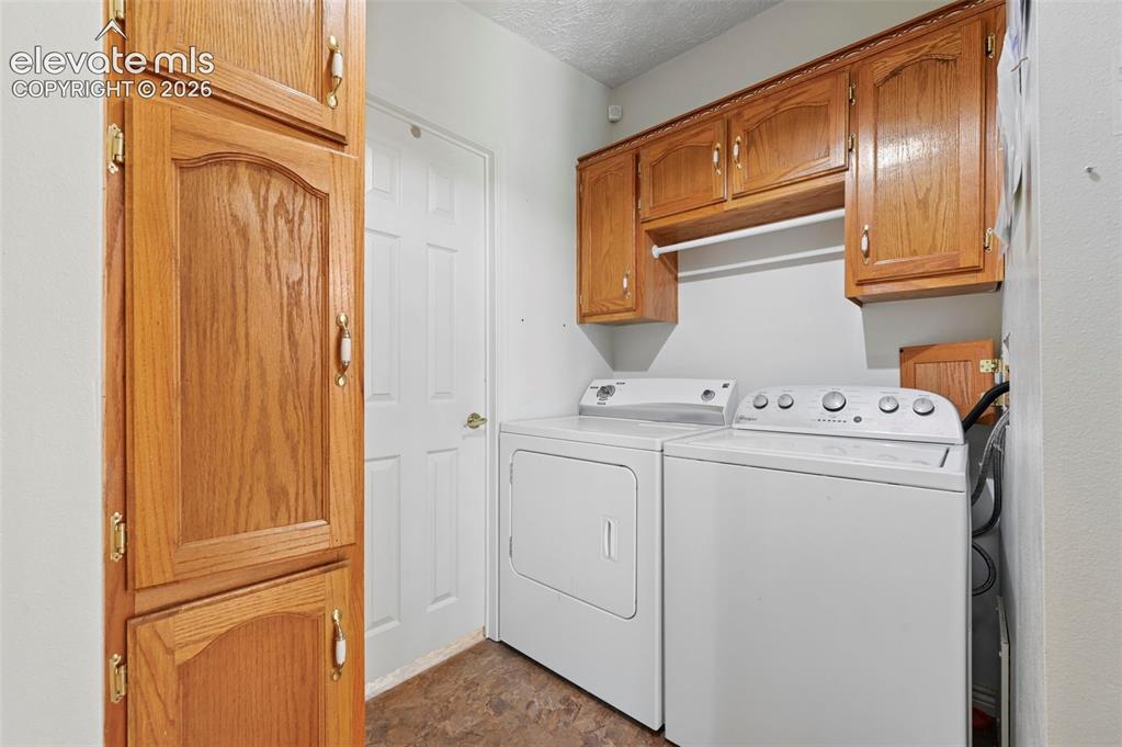 Image 22 of 38: Laundry area with wood-finish cabinetry, white appliances, and a built-in d