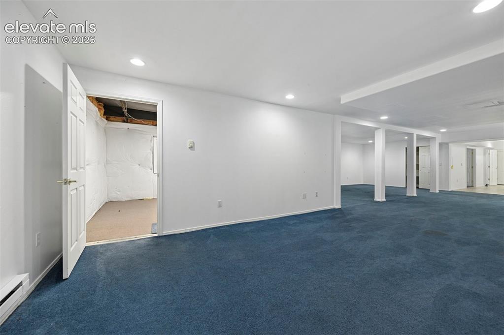 Image 24 of 38: Expansive carpeted area with recessed lighting, structural support columns,