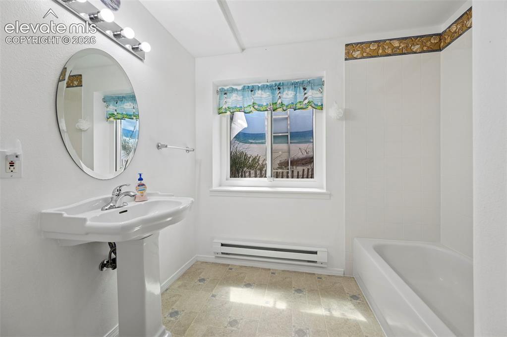 Image 29 of 38: Pedestal sink with chrome faucet, oval mirror, wall-mounted vanity lighting