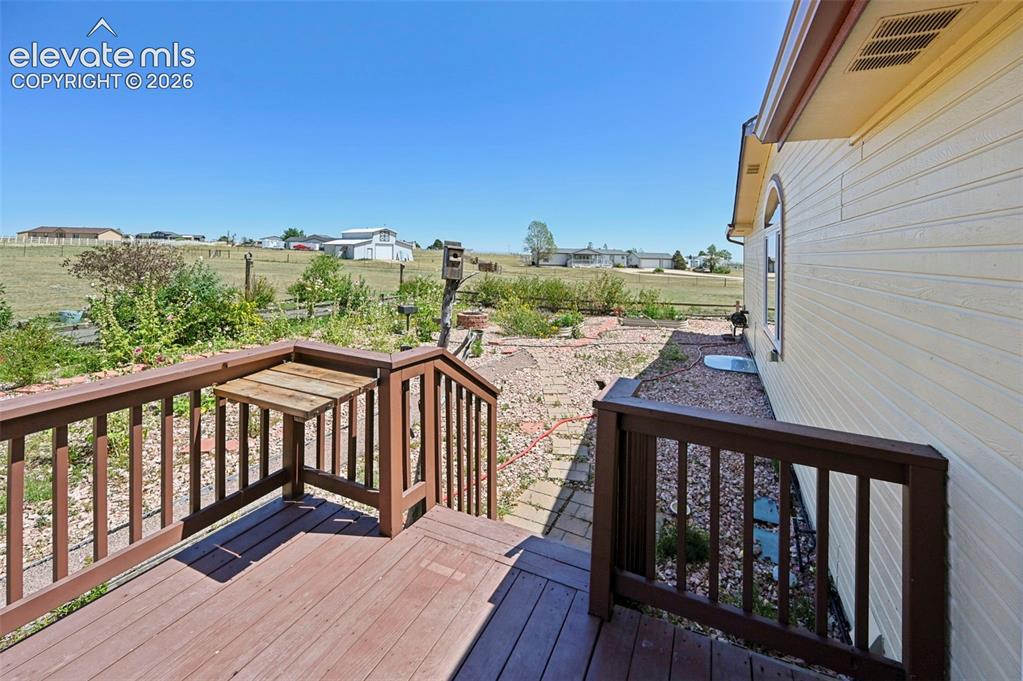 Image 35 of 38: Wood-finish deck with integrated drop-leaf table, exterior siding, and a ro