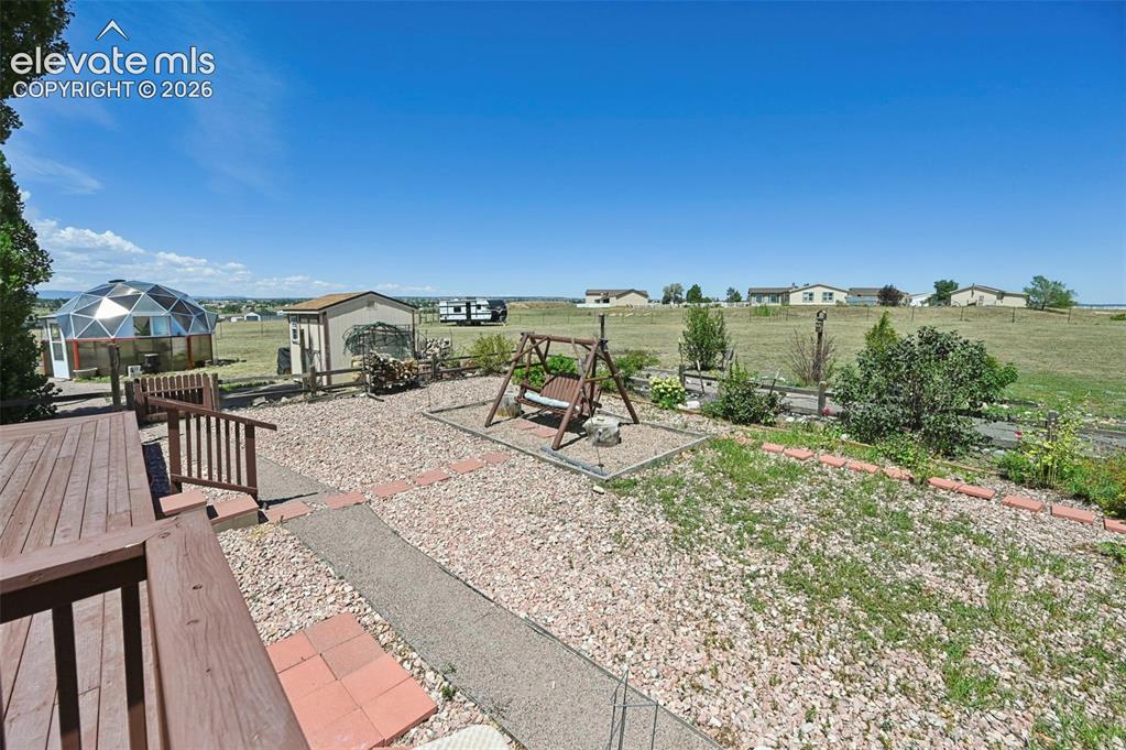 Image 36 of 38: Outdoor wood-finish decking and railing, geodesic dome structure, gravel la