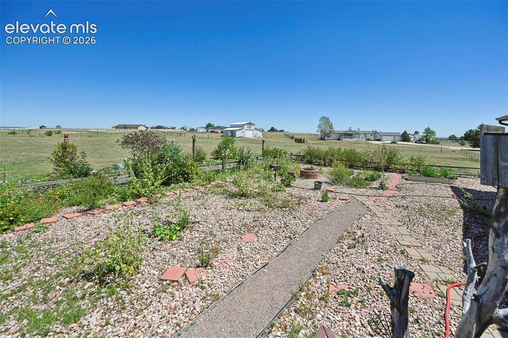 Image 37 of 38: Expansive backyard featuring a gravel landscape, brick-lined garden beds, a