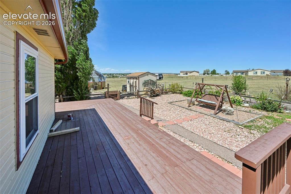Image 38 of 38: Expansive wood deck with railing, gravel ground cover, and a detached shed