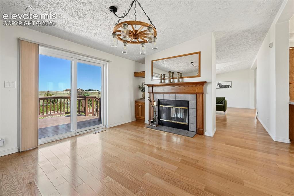 Image 7 of 38: Hardwood-finish flooring, a fireplace with a wood mantel and tile surround,