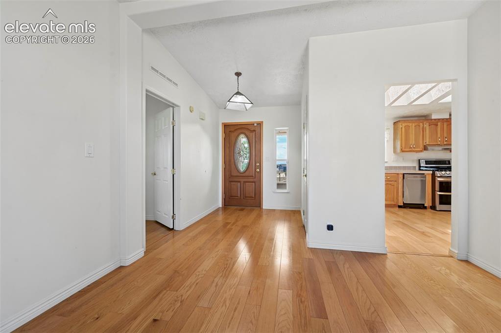 Image 9 of 38: Hardwood flooring throughout, vaulted ceiling, and an arched entry door wit