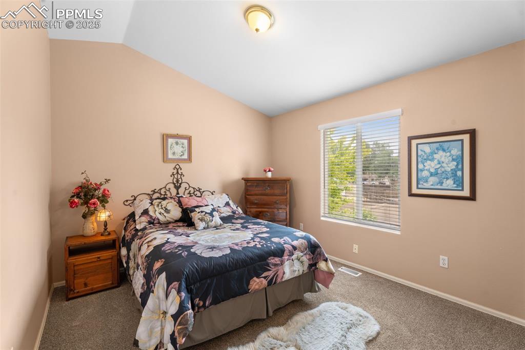 Image 19 of 32: Newly carpeted bedroom featuring lofted ceiling.