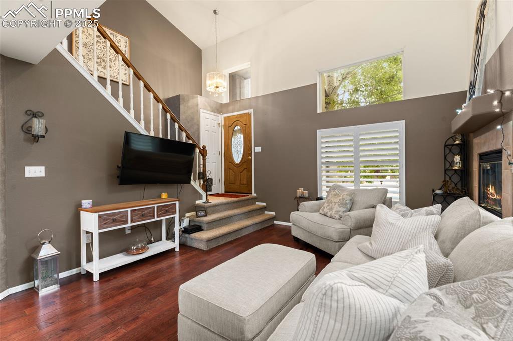 Image 4 of 32: Spacious living room showcasing dark wood-style floors, a cozy gas fireplac